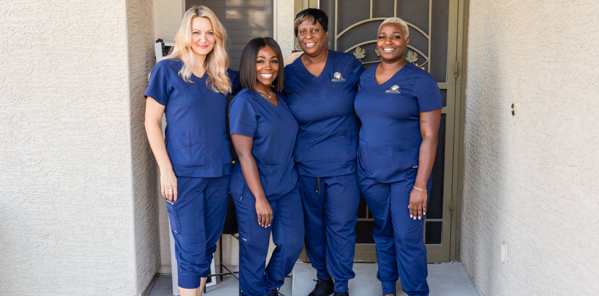 Four women in blue scrubs standing next to each other.