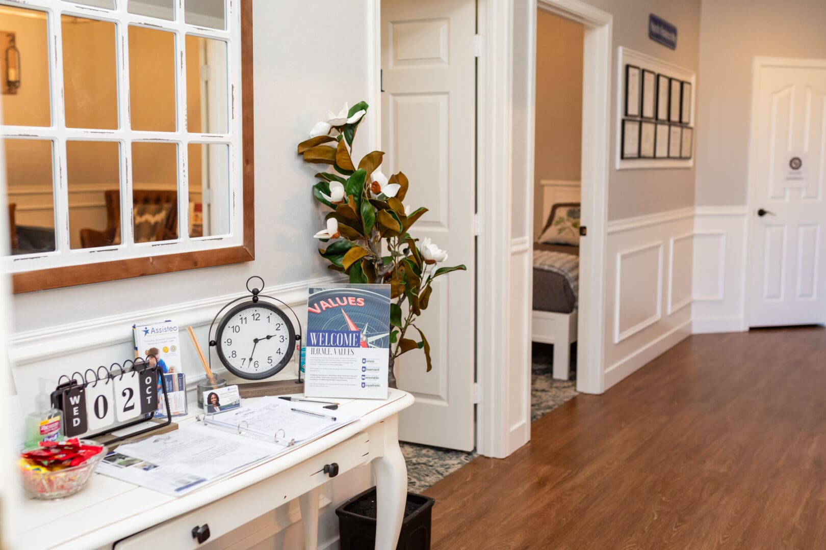 A white desk with a clock and some papers on it